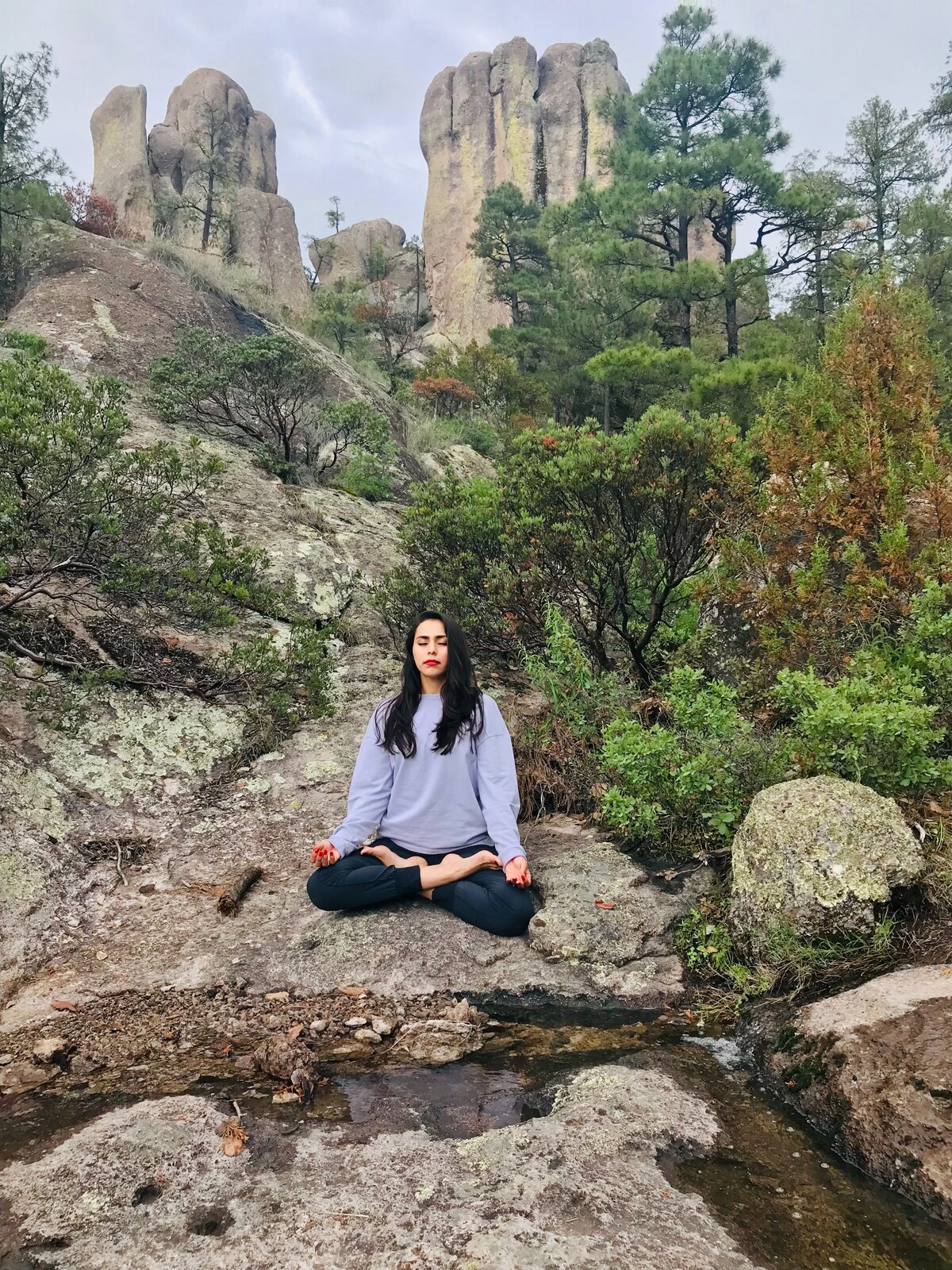 Isis meditando junto al agua entre las rocas y los pinos de la Sierra